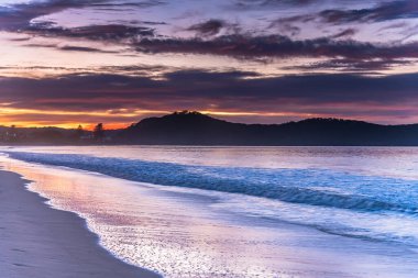 Sahilde renkli bir güneş doğuyor. Umina Sahili 'nden gelen bulutlar, NSW, Avustralya.