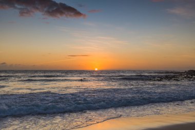 Kumsalda sabahın erken saatlerinde güneş ufuktan yükselirken MacMasters Sahili 'nden, NSW, Avustralya.