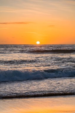 Kumsalda sabahın erken saatlerinde güneş ufuktan yükselirken MacMasters Sahili 'nden, NSW, Avustralya.