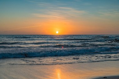 Kumsalda sabahın erken saatlerinde güneş ufuktan yükselirken MacMasters Sahili 'nden, NSW, Avustralya.