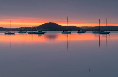 Katı bir bulut kütlesi gökyüzünü, Koolewong Rıhtımı 'ndan Avustralya, NSW, Avustralya' ya kadar renk çizgileriyle kapladı..