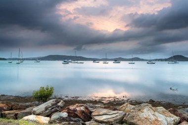 Bulutlar ve botlarla Sunrise Waterscape Koolewong, Central Coast, NSW, Avustralya.