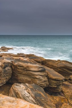 Central Coast, NSW, Avustralya 'daki Bouddi Ulusal Parkı' ndaki Putty Beach Burnu 'ndan bulutlu ve kasvetli bir gün doğumu..
