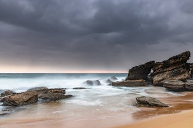 Central Coast, NSW, Avustralya 'daki Killcare Sahili' nden kayalarla kasvetli bir gün doğumu..