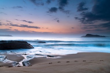 Sunrise Seascape 'de Central Coast, NSW, Avustralya' daki North Pearl Beach 'in kumlarında ayak izleri var..