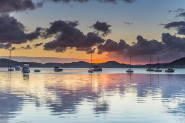 Renk ve yansıma ipuçları içeren bulutlu bir su manzarası - Koolewong Rıhtımı 'ndan gündoğumu Merkez Sahili, NSW, Avustralya.