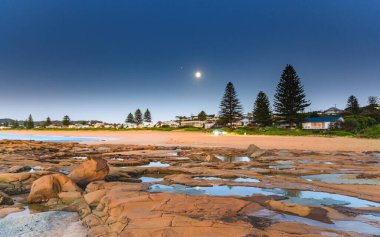 Güneşin doğuşunu ve 99.7 Waning Gibbous Ayını Central Coast, NSW, Avustralya 'daki North Avoca Sahili' nden çekiyoruz..