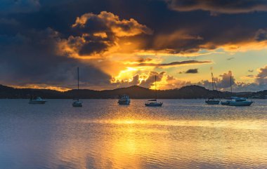 Central Coast, NSW, Avustralya 'daki Koolewong rıhtımından gelen teknelerle bulutlu su doğuyor..