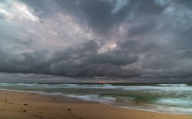 Kumsalda ve denizde gökyüzü bulutla doldu. Kuzey Girişi Sahili 'nde Şafak Denizi Girişi, Merkez Kıyı, NSW, Avustralya