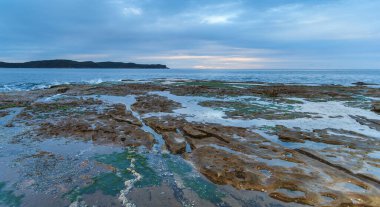 Pearl Beach, Central Coast, NSW, Avustralya 'daki kaya sahanlığından bulutlu şafak deniz manzarası.