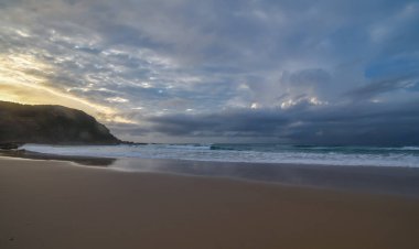 Bulutlu, plajda güne başlıyor. Birdie Beach 'te çekildi, Munmorah Central Coast' da, NSW, Avustralya.