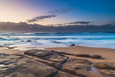Low Tide sahilinde kayalar bulundu - Orta Sahildeki MacMasters Sahili 'nden gün doğumu, NSW, Avustralya.