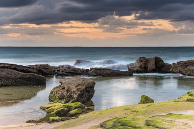 Central Coast, NSW, Avustralya 'daki Killcare Sahili' nde gündoğumu ve yosunlu yeşil kayalar..