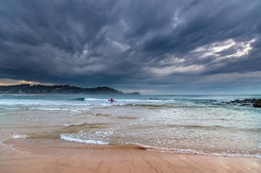 10 Temmuz 2020: Deniz kıyısında, sabahın erken saatlerinde sörfçüler, yüzücüler ve Avoca Sahili 'nden gelen bulutlarla dolu bir gökyüzü, NSW, Avustralya.