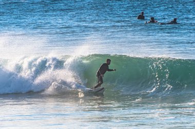 Shelly Plajı, NSW / Avustralya - 6 Haziran 2020: Diğerleri sırasını beklerken sörfçü bir dalga yakalıyor.