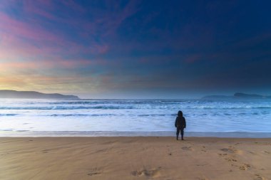 Umina Plajı, NSW / Avustralya - 19 Temmuz 2020: Sahilde gün doğumu Orta Sahildeki Umina Sahili 'nde denize bakan bir çocukla, NSW, Avustralya.