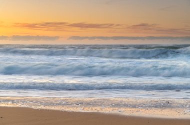 Kışın deniz kenarında dalgalar ve yumuşak ışık bulutları Orta Sahildeki Killcare Sahili 'nde, NSW, Avustralya.