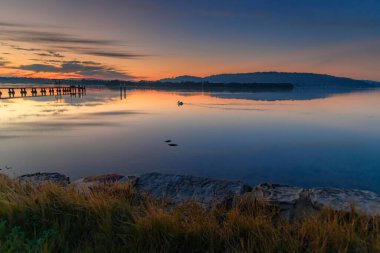 Gündoğumu, yüksek bulutlu ve yansımalı su manzarası Orta Sahildeki Woy Woy rıhtımında, NSW, Avustralya.
