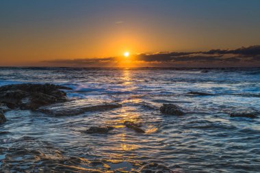 Sahilde altın gün doğumu Orta Sahildeki Toowoon Körfezi Sahili 'nden gelen kreusküler ışınlarla, NSW, Avustralya.