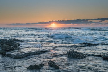 Sahil kenarında gün doğumu Orta Sahildeki Toowoon Körfezi Sahili, NSW, Avustralya 'dan kayalık bir kıyı şeridiyle..