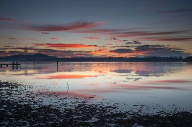 Gündoğumu, yüksek bulutlu ve yansımalı su manzarası Orta Sahildeki Woy Woy rıhtımında, NSW, Avustralya.