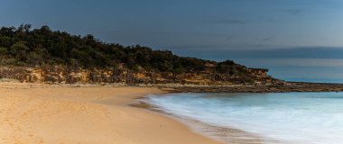 Central Coast, NSW, Avustralya 'daki Bouddi Ulusal Parkı' ndaki Putty Plajı 'nda bulutlu bir gün batımı..