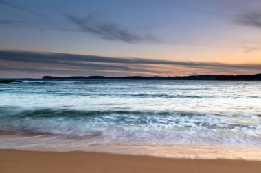 Central Coast, NSW, Avustralya 'daki Bouddi Ulusal Parkı' ndaki Putty Plajı 'nda bulutlu bir gün batımı..