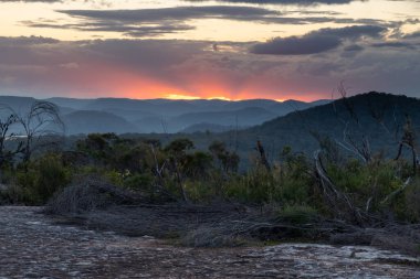 Avustralya, NSW 'nin merkez kıyısında, Patonga ve Pearl Beach arasındaki Bouddi Ulusal Parkı' nda Tessellated Rock Pavement ile çalılıklarda gün batımı..