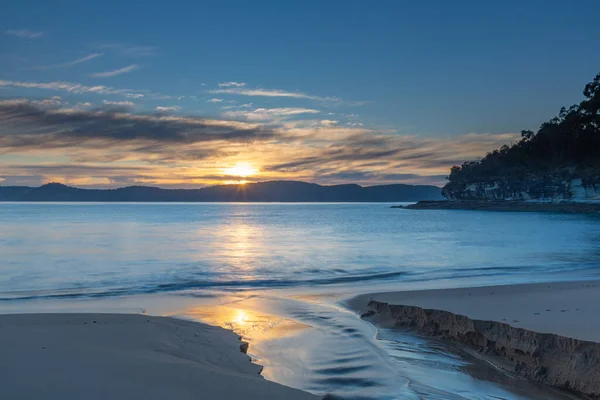 Sakin denizler ve yumuşak bulutlar gündoğumunu gölden süzülen suyla karşıladı. Central Coast, NSW, Avustralya 'daki Pearl Beach' e geri döndü..