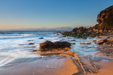 Gündoğumu deniz manzarası yeni taşlarla örtüldü ve kumsaldaki erozyondan sonra Central Coast, NSW, Avustralya 'daki Killcare Sahili' nde yer değiştirdi..