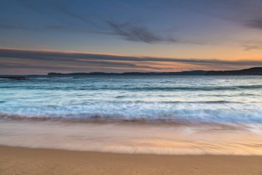 Central Coast, NSW, Avustralya 'daki Bouddi Ulusal Parkı' ndaki Putty Plajı 'nda bulutlu bir gün batımı..