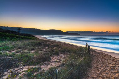 Gündoğumu deniz manzarası yeni taşlarla örtüldü ve kumsaldaki erozyondan sonra Central Coast, NSW, Avustralya 'daki Killcare Sahili' nde yer değiştirdi..