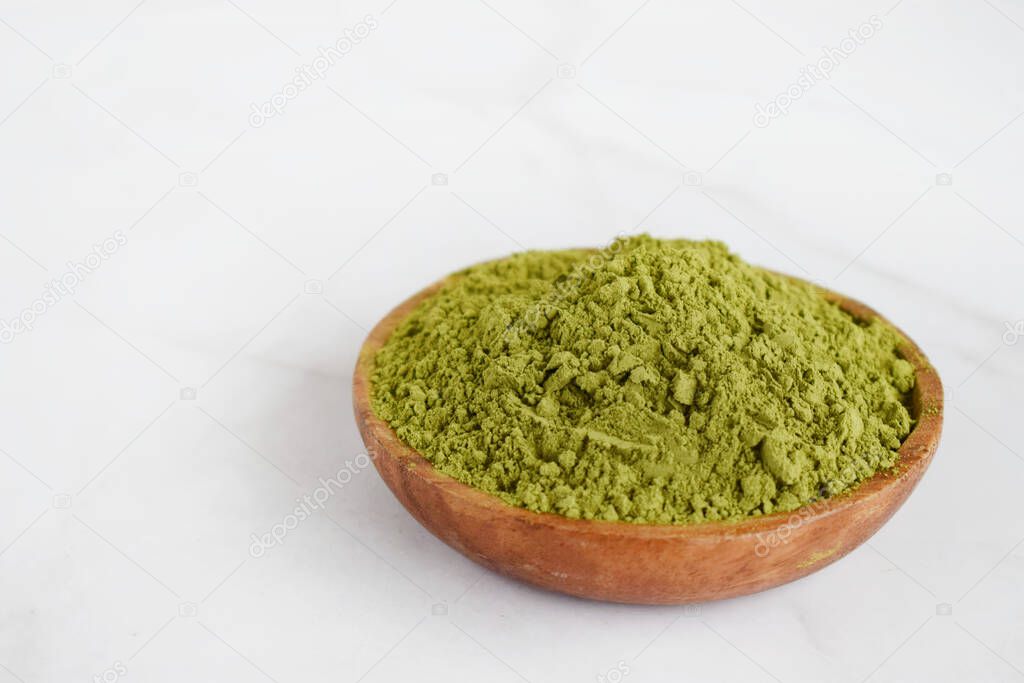 Moringa powder in wooden bowl on white background. Healthy product, superfood, vitamin Moringa Oleifera.