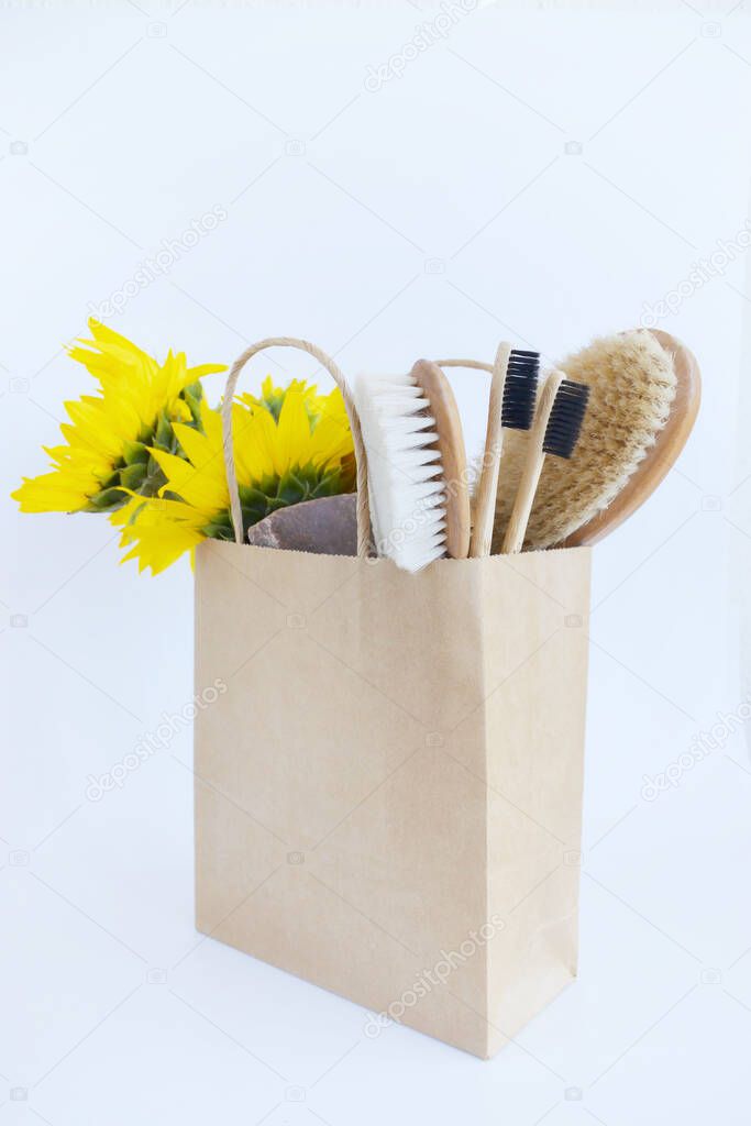 Zero waste concept. Paper bag, bamboo toothbrushes, handmade soap, body brush and ear sticks on white background. Sustainable living. Eco friendly plastic free items. plastic-free,eco-friendly cleaning products. Sunflowers in paper bag.