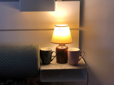 Masa lambası, kahve fincanı ve yatak odası masanın üstünde.