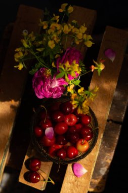 Çiçekler, kirazlar ve kirazların yanı sıra dutlardan oluşan natürmort yaşam bileşimi