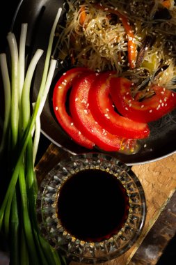 Siyah tabakta soya sosu ve ahşap bir masada yeşil soğan.