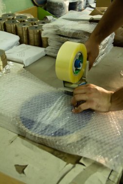 Metal ürünleri ve elleri yapıştırıcı bant ile paketliyorum.