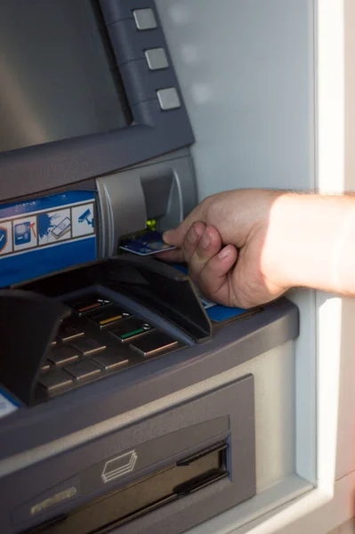 Male hand inserting a bank card into an ATM machine