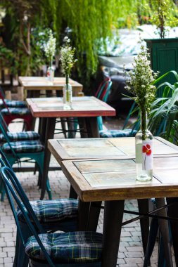 Cafe masaları ve sandalyeler Provence tarzında şişelerde çiçeklerle