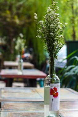 Bir sokak kafesinin sütunlarında şişeler içinde çiçekler