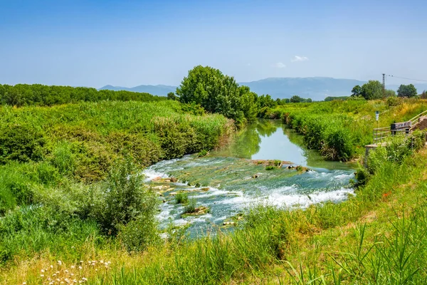 La campagna intorno al piccolo borgo antico di Cannara in provincia di Perugia, Umbria, Italia con il fiume Topino e campi coltivati