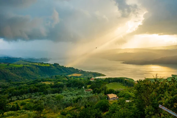 Un raggio di sole diretto verso l\'acqua durante un tramonto coloratissimo e scenografico sul lago di Corbara, Umbria, Italia