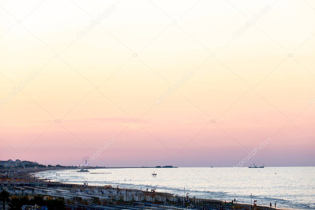 Minimal landscape of Adriatic sea shore in Rimini and Riccione at sunset, with colorful sky and the panoramic wheel on background
