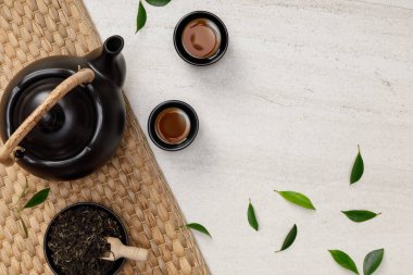 Çaydanlıklı çay fincanı, organik yeşil çay yaprakları ve beyaz taşın üzerinde kurumuş otlar boş uzay yaratıcı düz yatak, doğadan gelen organik ürün geleneksel tarzda sağlıklı olmak için.