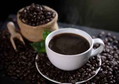 Tahta masada kahve çekirdekleri olan sıcak kahve fincanı.