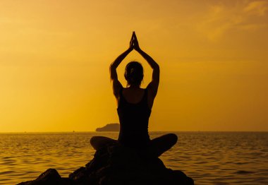 Genç, formda bir kadın, güneş doğarken meditasyon ve refah için yoga tekniğini kullanıyor.