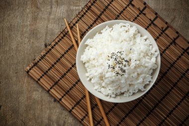 Buharda pilav ve bambu hasırı, organik gıda ve sağlıklı konsept üzerine çubuklu siyah susam tohumları.