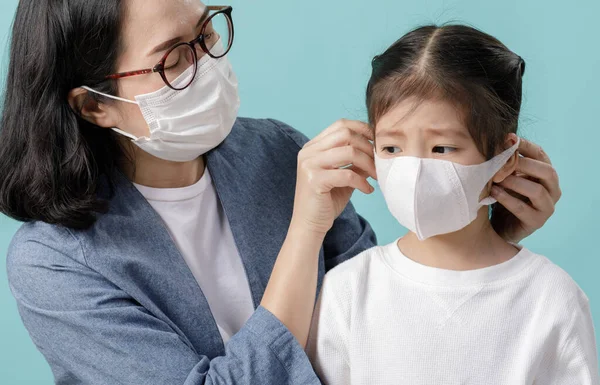 ママとアジアの小さな子供の女の子は 汚染から身を守るために医療面のマスクを着ていますコロナウイルスインフルエンザウイルス 中国からの新しいコロナウイルス2019 Ncv 青い背景に隔離された空のスペース — ストック写真