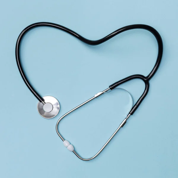 Mavi masa arkasında kalp şeklinde steteskop, Doktor konseptinden sağlık, mavi üzerine izole edilmiş üst manzara.